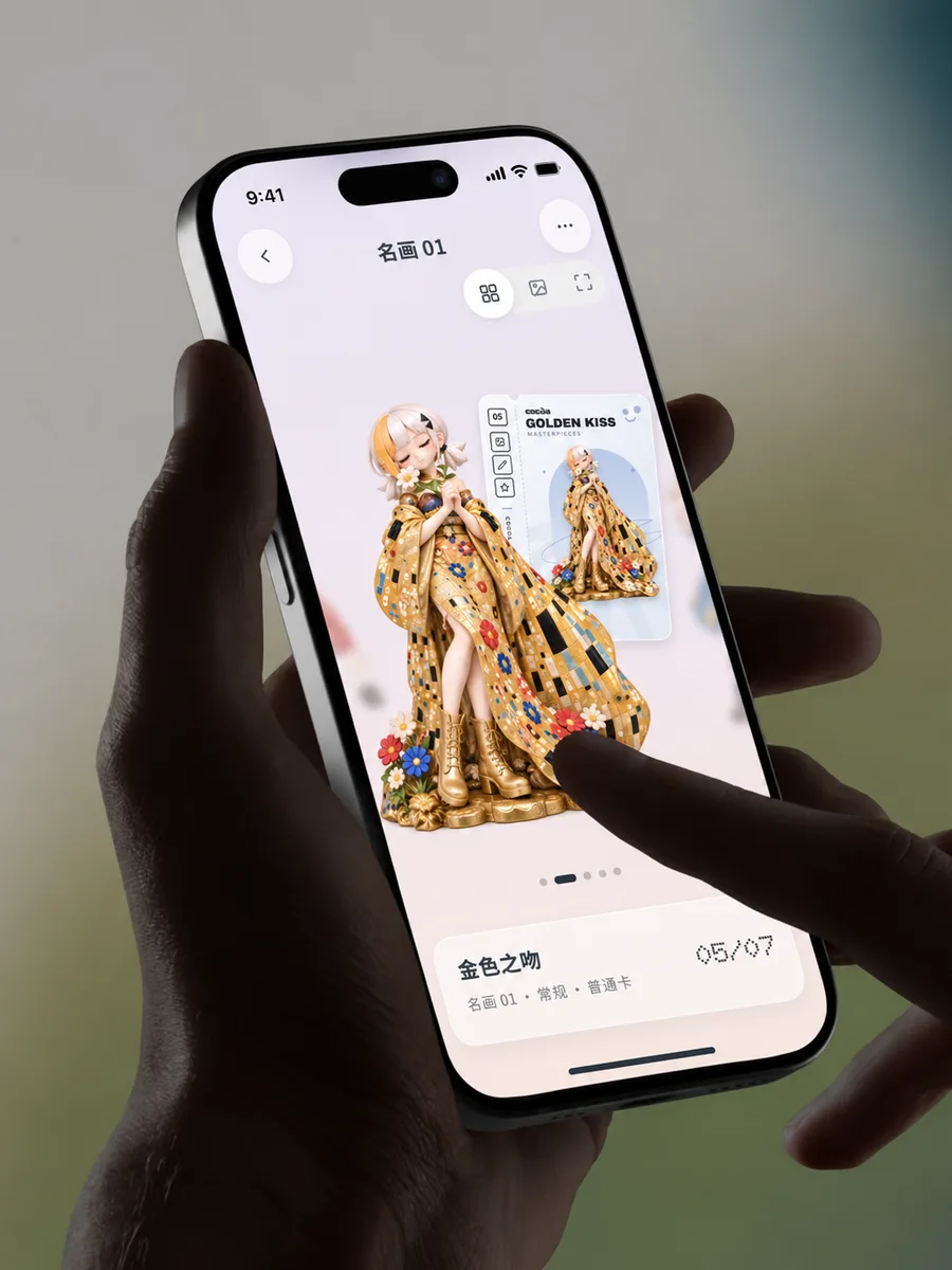 A hand holding a phone showing Golden Kiss, figure 05 of 07, next to its card